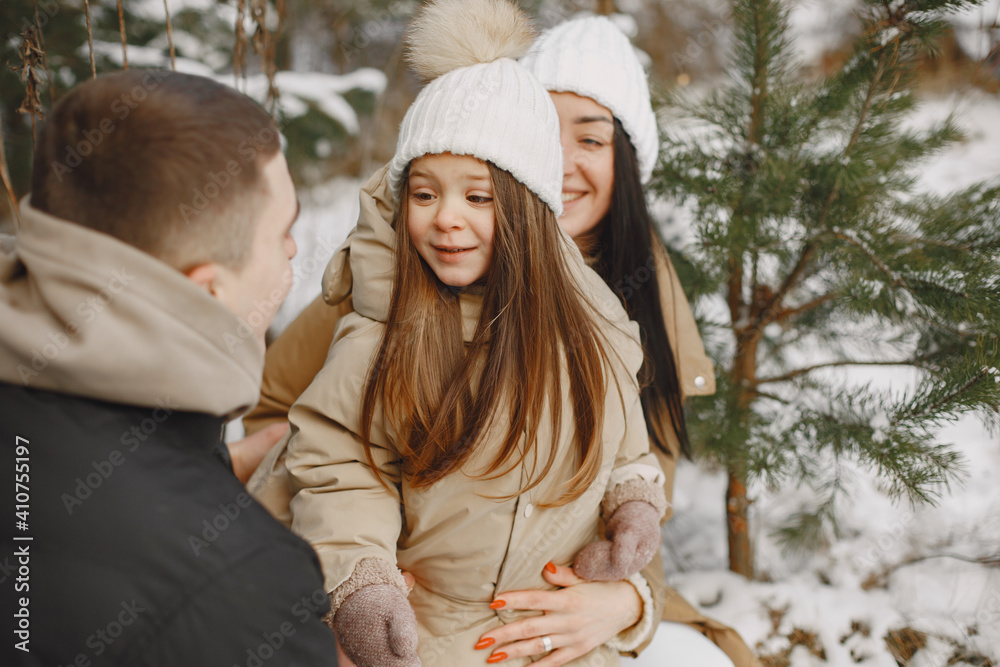 Obraz premium Family in knitted winter hats on family Christmas vacation. Parents and little girl in a park. People walks.