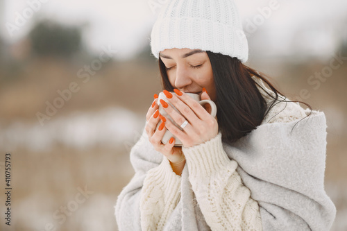 Close-up portrait of woman in white sweater. Woman standing in snowy day. Girl with tea.
