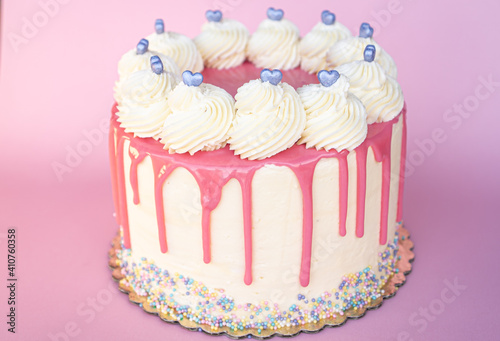 Exquisite Valentine's Day cake decorated with pink icing with heart-shaped candies on top.