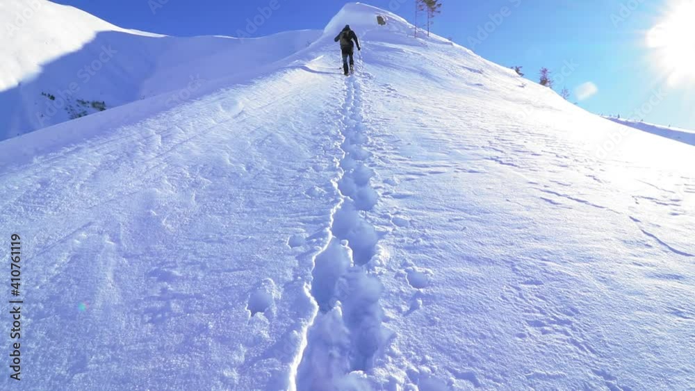 A slow motion of a hiker climbing the snowy mountain on a sunny day in HD