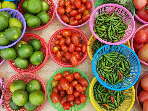 Cherry tomatoes, limes, green and red bell peppers are all organic products grown from the villagers' back gardens Place them in round baskets for distribution to customers in vegetable shops. 