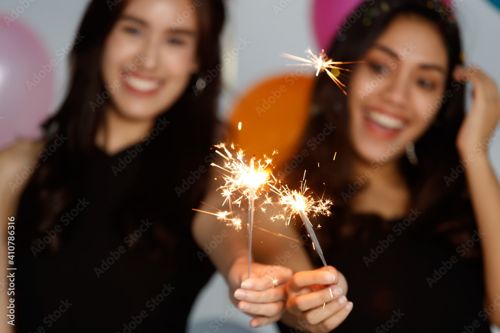 Two young and beautiful sexy Asian girls in a black dress playing with small little fireworks with fun and happiness in celebrating party Two young and beautiful sexy Asian girls in a black dress playing with small little fireworks with fun and happiness in celebrating party