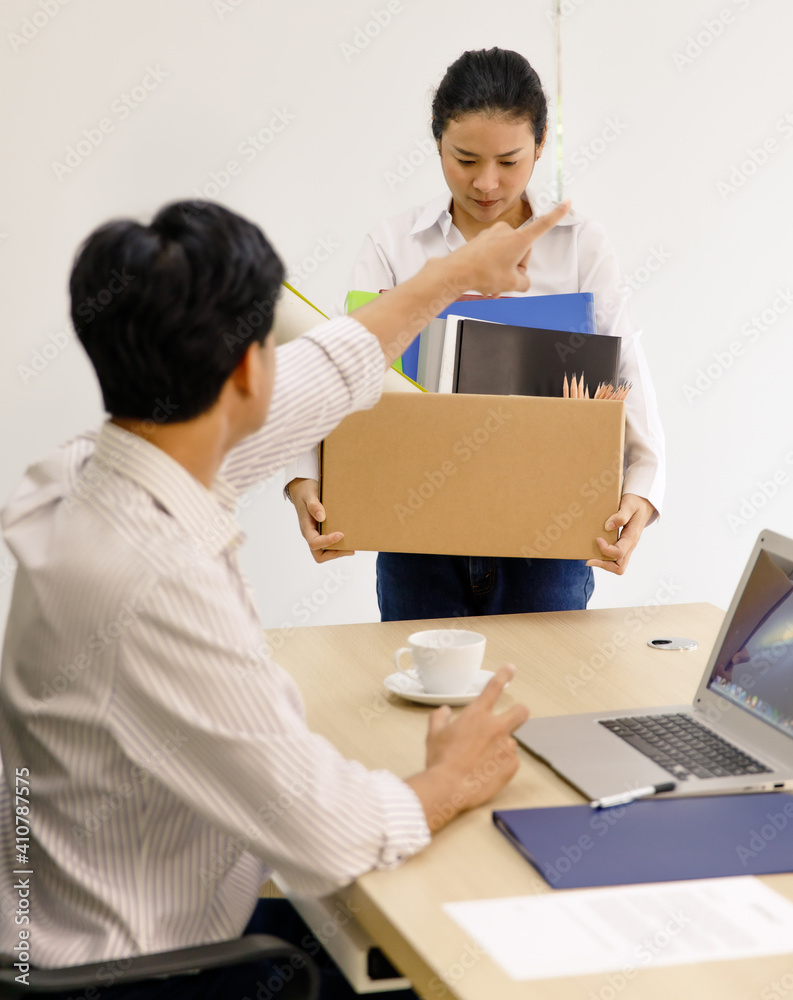 young Asian female worker wearing a white shirt carries a box of personal stuff with an unhappy face lose a job gets fired due to the Covid-19 crisis. Unemployment economic recession concept young Asian female worker wearing a white shirt carries a box of personal stuff with an unhappy face lose a job gets fired due to the Covid-19 crisis. Unemployment economic recession concept