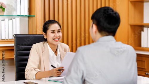 young attractive Asian businesswoman dressed smart casual smiling friendly and cheerful to the applicant during the interview in a company office. Confident and successful people concept