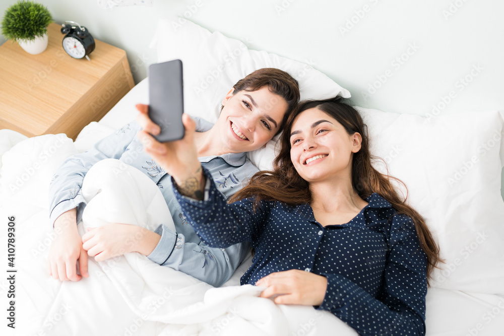 Two smiling young women taking a photo in bed Two smiling young women taking a photo in bed