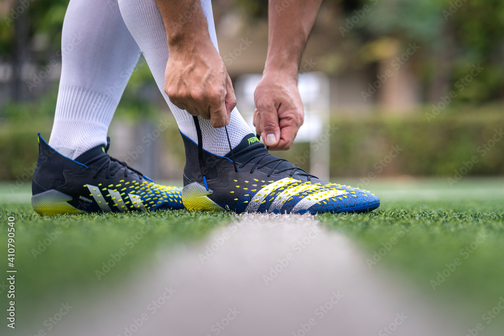 Bangkok, Thailand - January 2021 : A football player is wearing adidas  "Predator Freak" which is design for striker feature on turf training  ground. Close-up and selective focus, sport action photo. Stock