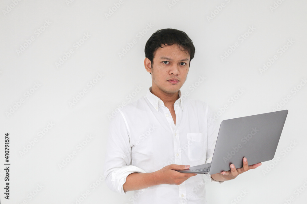 Young Asian man is Angry and hate with laptop. Indonesia Man wear white shirt Isolated grey background.
