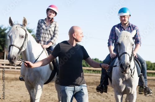 Positive mature couple with jockey learn to riding horse at farm outdoor