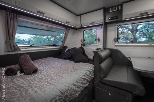 Interior view of a Double bed and club lounge area of a modern caravan at an outback campsite photo