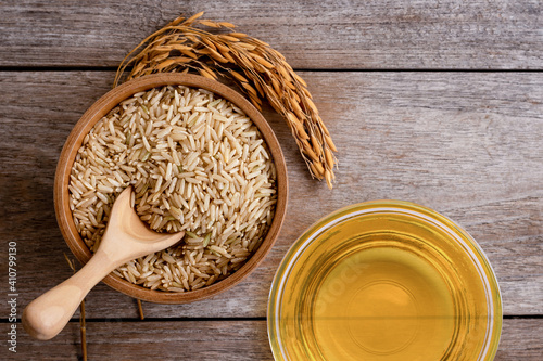 Rice bran oil extract with paddy and brown rice on wood table background. Top view. Flat lay. photo