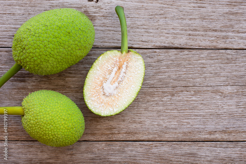 Breadfruit ( Artocarpus altilis ) with cut in half slice on wood table background. Top view. Flat lay. photo