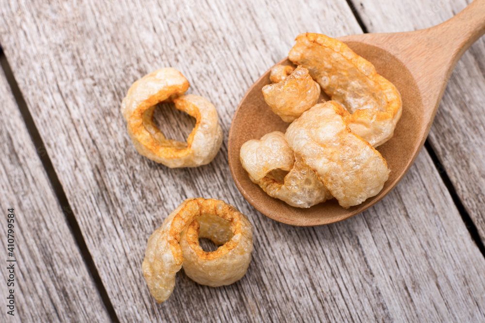Fried pork snack ( pork rind, pork cracking ) isolated on wood table background. Top view. Flat lay.