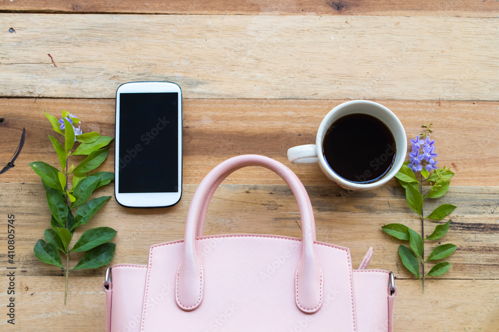 mobile phone ,hot coffee and pink hand bag of lifestyle woman relax arrangement flat lay style on background wooden