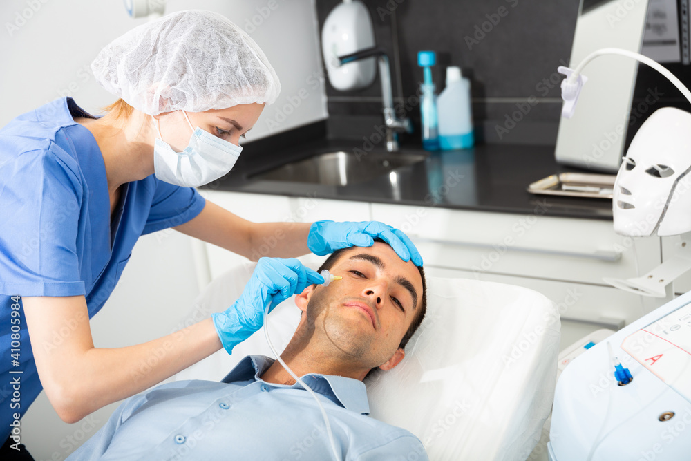 Obraz premium Professional beautician performing innovative anti-aging carboxytherapy procedure for facial skin to male client in aesthetic medicine cabinet.