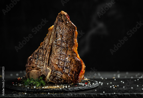 Grilled T-bone steak on stone table. juicy steak rare beef with spices on a black table, banner, menu, recipe, place for text photo