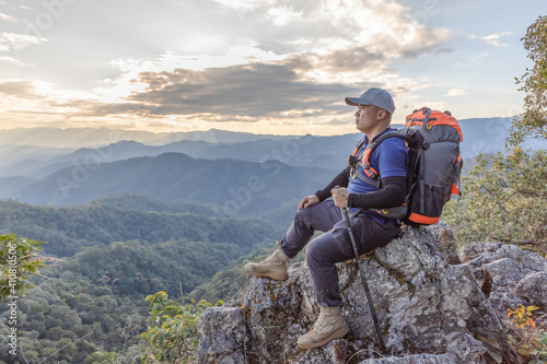 Young male hiker with backpack relaxing on top of a rock mountain