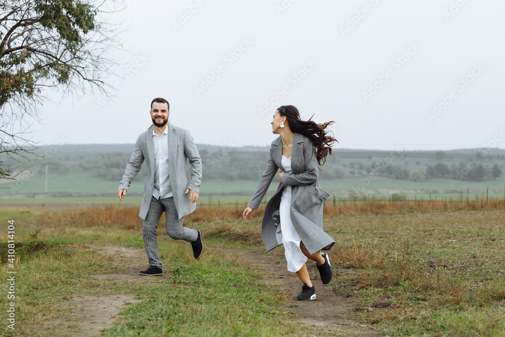 A mischievous couple of newlyweds are running around and having fun in the countryside. Happy moments of the wedding day.