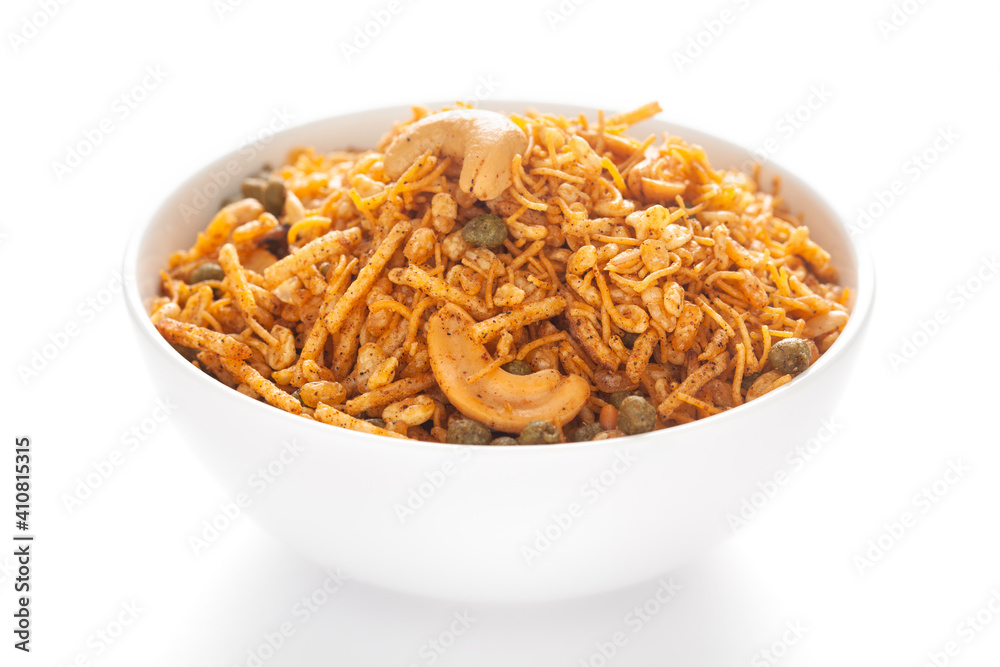 Hot spicy Kashmiri Mixture (Namkeen) snacks in a white ceramic bowl made with dry fruits, peanuts, corn flakes, etc. Pile of Indian spicy snacks, under backlight, side view Hot spicy Kashmiri Mixture (Namkeen) snacks in a white ceramic bowl made with dry fruits, peanuts, corn flakes, etc. Pile of Indian spicy snacks, under backlight, side view