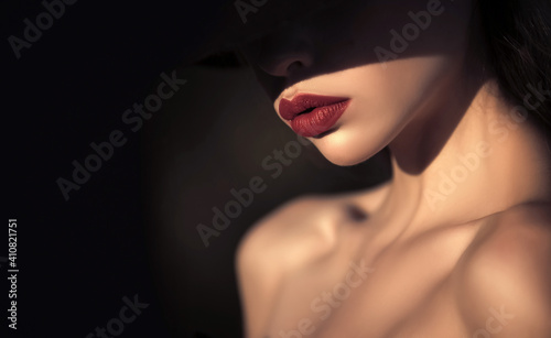 Woman in shadows. Elegant woman with red lips. elegant woman with naked shoulders on black background, copy space.