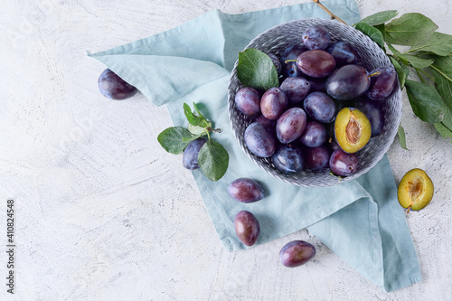 Bowl with tasty plums on light background photo