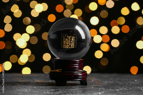 Crystal ball of fortune teller on dark background with blurred lights