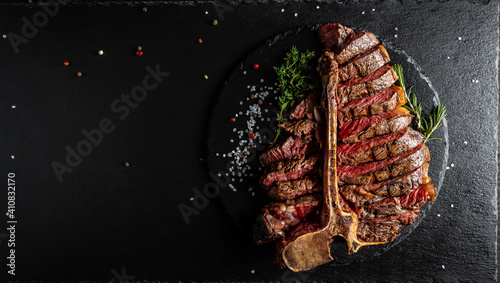 Barbecue dry aged wagyu porterhouse steak, grilled medium rare beef steak with spices served on slate board. sliced. Long banner format, top view