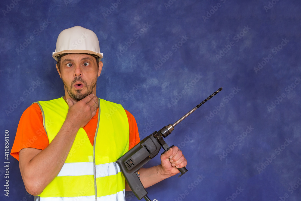 Male locksmith, builder. A worker with a tool in his hands and in working uniform.