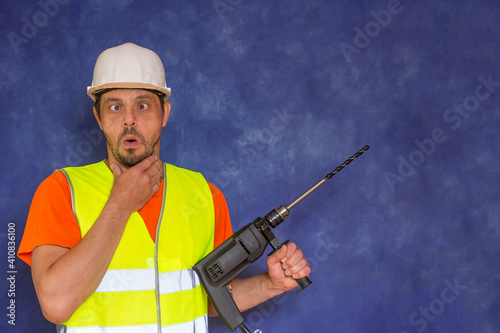 Male locksmith, builder. A worker with a tool in his hands and in working uniform. © Sergei