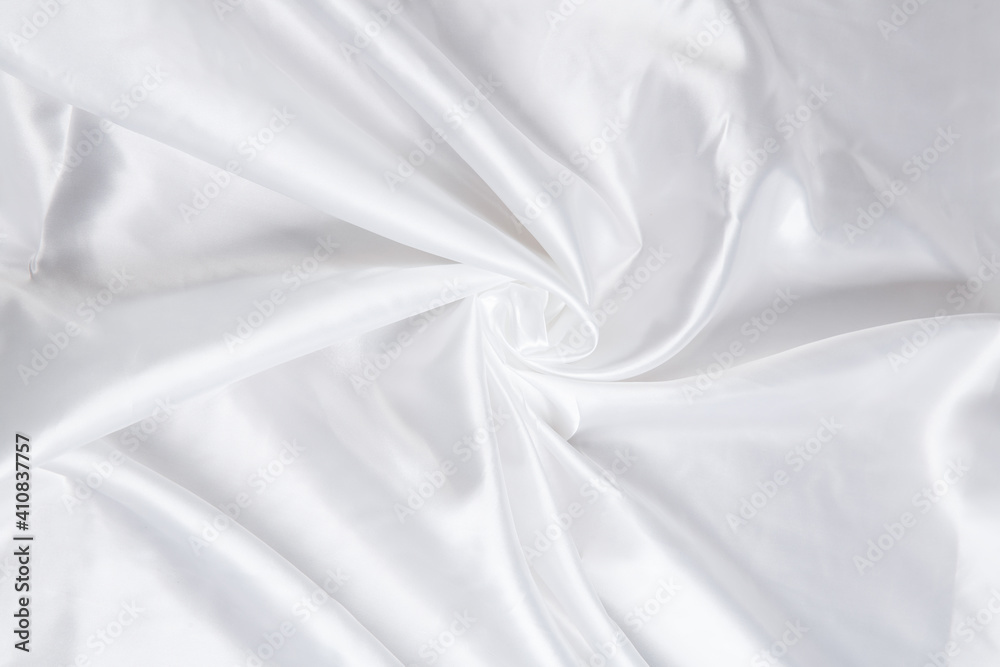 Obraz premium Colored white textile satin fabric folded in folds and waves with highlights and texture