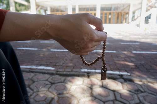 Muslim woman praying close up image of hands as she holds prayer beads, tasbih