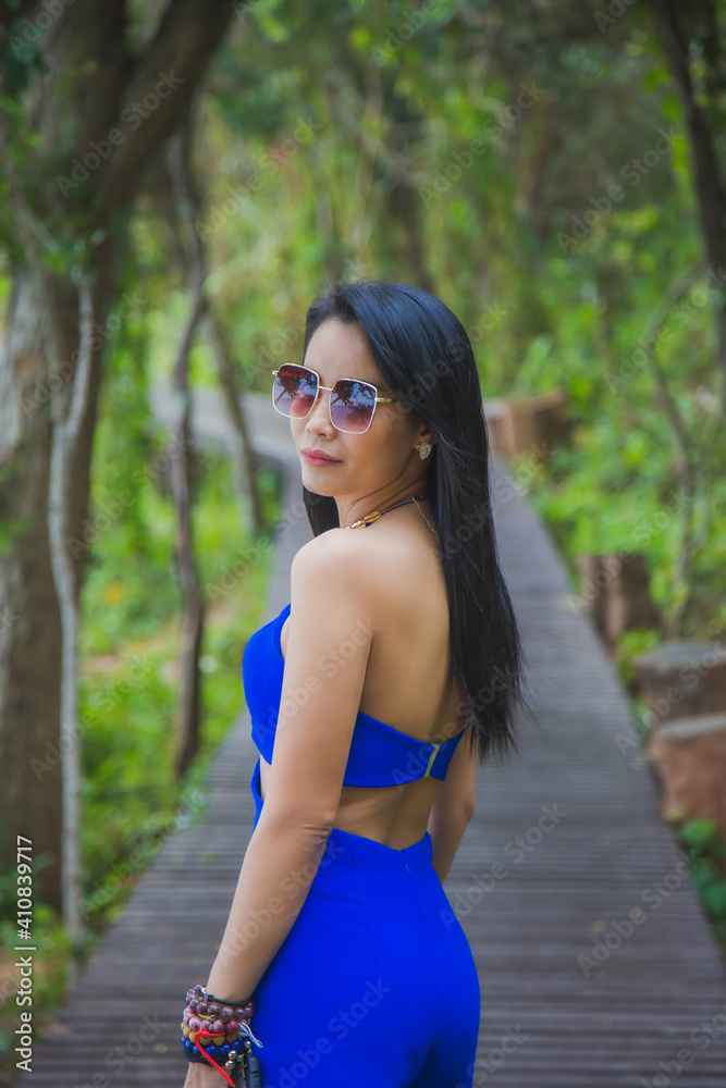 Portrait Asian woman in a blue suit standing on a wooden coastal bridge with a nature background. Portrait Asian woman in a blue suit standing on a wooden coastal bridge with a nature background.