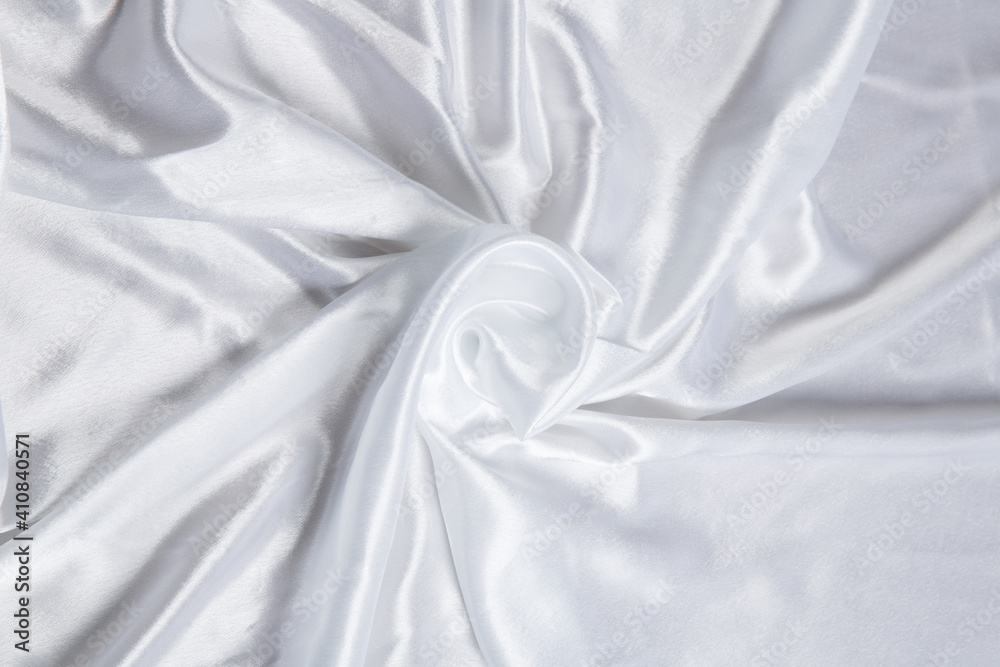 Colored white textile satin fabric folded in folds and waves with highlights and texture Colored white textile satin fabric folded in folds and waves with highlights and texture