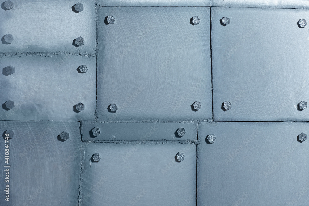 Background of silvery wall made of polyethylene foam sheets imitating metal with rivets.