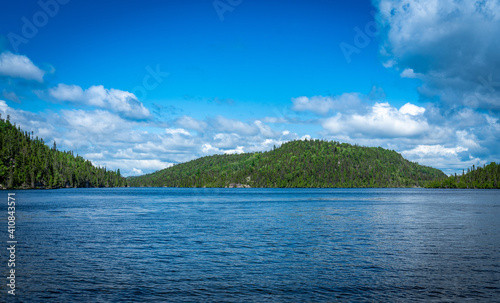 Wallpaper Mural Blue lake in Quebec Province, Canada, with green forest on a hill in the background on a sunny day and blue sky  Torontodigital.ca