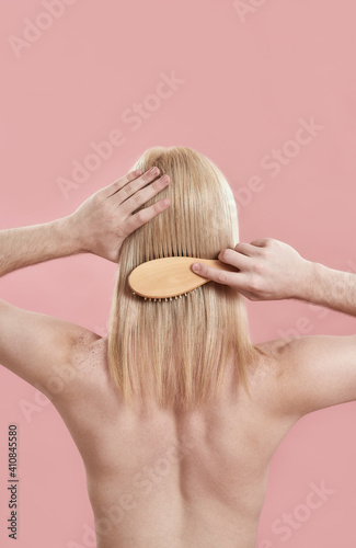 Rear view of young man combing his long blond hair