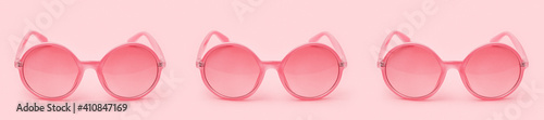 Three sunglasses in a row on a pink background