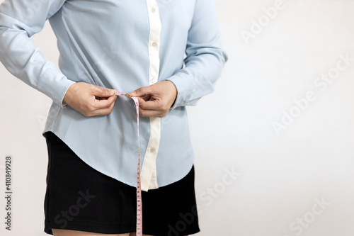 Close up,belly of female,asian young woman hold tape measure check waistline,healthy girl measuring around waist size with tape,waist measurement for fat checking,health care,weight control concept photo