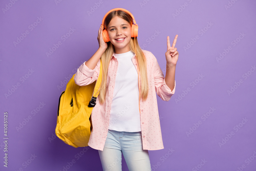 Photo of optimistic long hairdo pretty girl show v-sign wear rucksack headphones pink shirt isolated on violet color background Photo of optimistic long hairdo pretty girl show v-sign wear rucksack headphones pink shirt isolated on violet color background