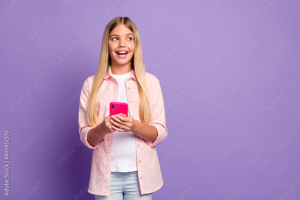 Photo of optimistic long hairdo pretty girl hold telephone look empty space wear pink shirt isolated on violet color background Photo of optimistic long hairdo pretty girl hold telephone look empty space wear pink shirt isolated on violet color background