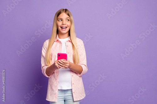 Photo of optimistic long hairdo pretty girl hold telephone look empty space wear pink shirt isolated on violet color background