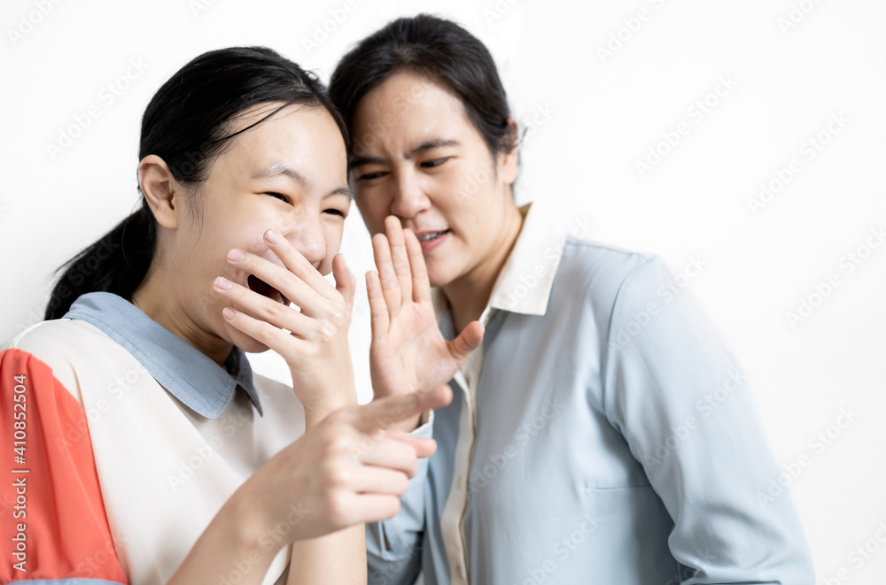Asian woman gossiping slander in girl ear,aspersion, defamation,speak to scornful abuse,negative facial expression,female student pointing the finger with the hand covering the mouth laughing ridicule Asian woman gossiping slander in girl ear,aspersion, defamation,speak to scornful abuse,negative facial expression,female student pointing the finger with the hand covering the mouth laughing ridicule
