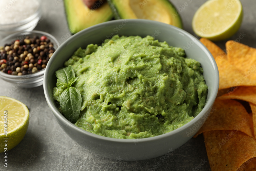 Concept of tasty eating with guacamole and ingredients on gray background Concept of tasty eating with guacamole and ingredients on gray background