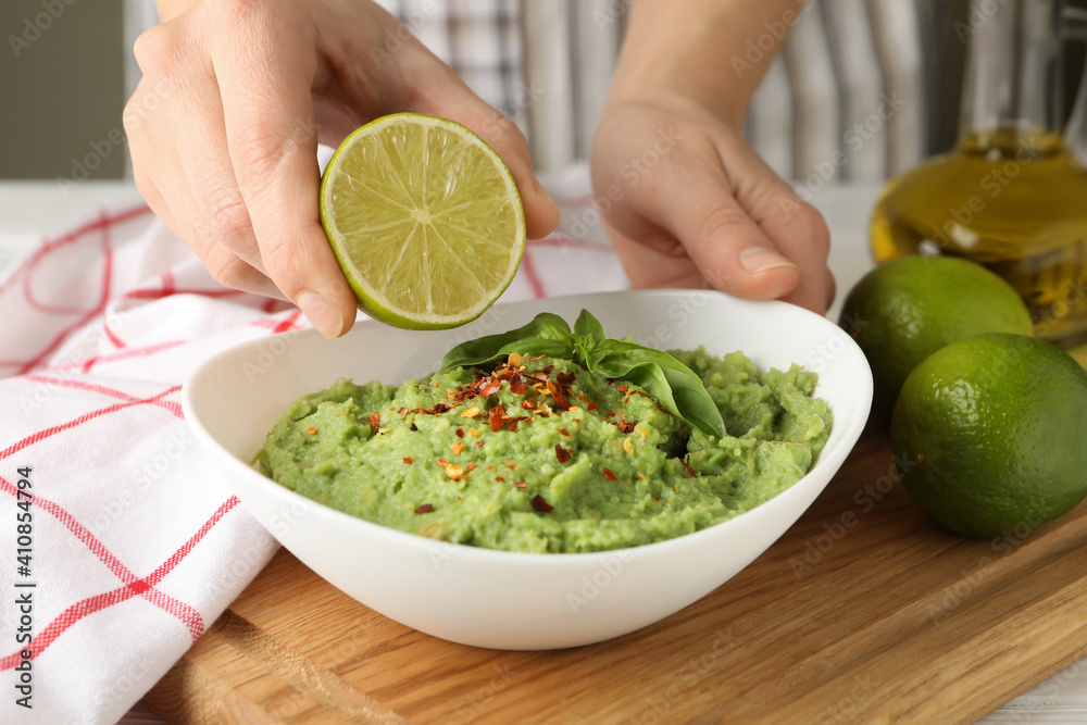 Female hands hold lime and bowl with guacamole Female hands hold lime and bowl with guacamole