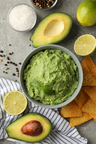 Concept of tasty eating with guacamole and ingredients on gray background