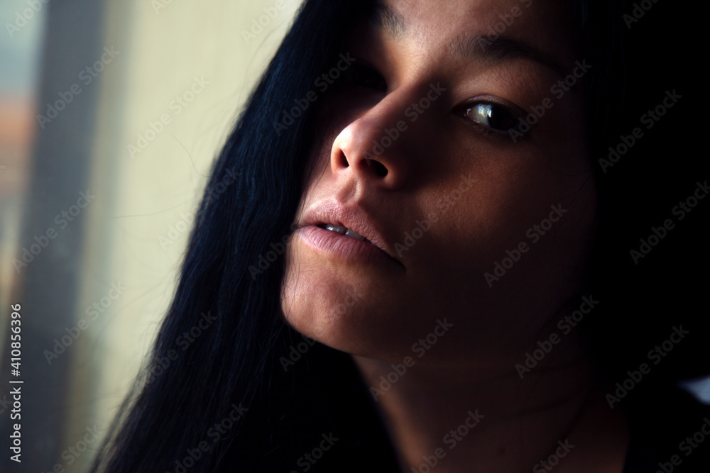 Portrait of a beautiful brunette woman with long hair. Self-portrait. Natural light from the window
