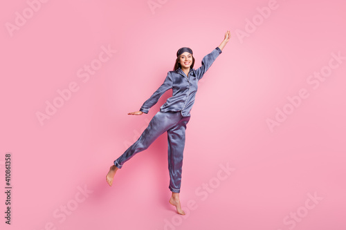 Full length body size photo of girl wearing blue sleepwear jumping imagine keeping umbrella smiling isolated on pastel pink color background