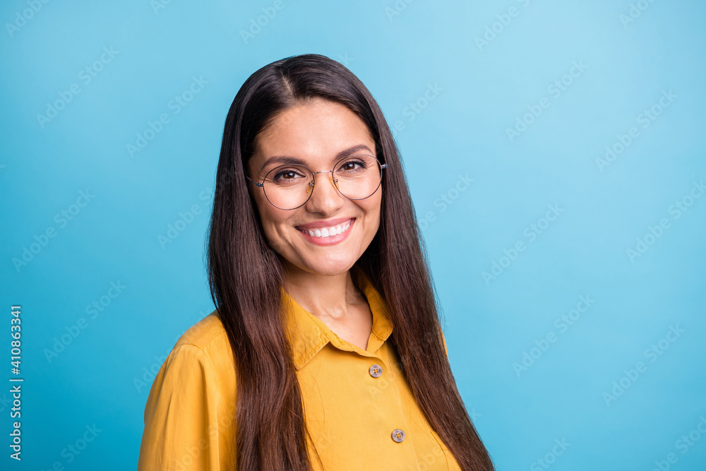 Photo of half turned satisfied person look camera beaming smile eyewear isolated on blue color background Photo of half turned satisfied person look camera beaming smile eyewear isolated on blue color background