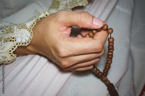 Muslim woman praying close up image of hands as she holds rosary beads or prayer beads, tasbih