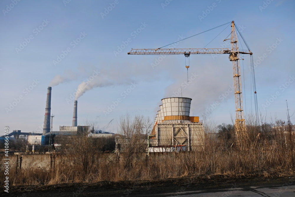 Almaty, Kazakhstan - 02.04.2021 : Cooling tower, Smoking chimneys and tower crane to the district heating