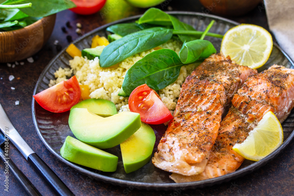 Grilled salmon fillet close-up with couscous, salad fresh vegetables and avocado on dark background. Grilled salmon fillet close-up with couscous, salad fresh vegetables and avocado on dark background.